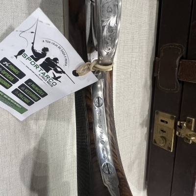 Detalhe de espingarda com gravações e etiqueta da SPORTARCO pendurada