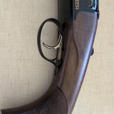 Espingarda com coronha em madeira e gatilho de metal preto com texto 'Perazzi HIGH TECH' no cano