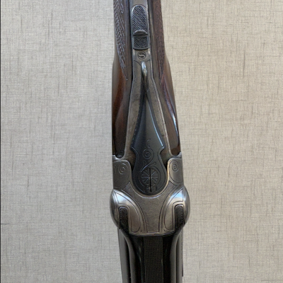 Espingarda de madeira e metal com gravações e botão 'S'.