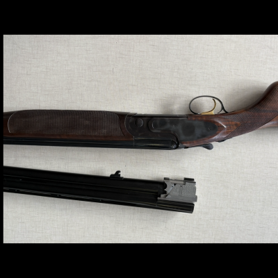 Espingarda de canos duplos em madeira escura e metal preto com gatilho dourado