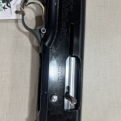 Espingarda preta com cabo de madeira e texto BERETTA MADE IN ITALY