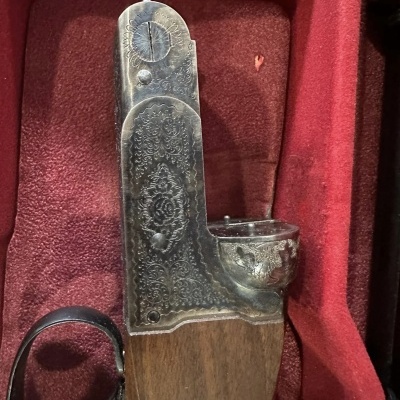 Parte de arma de fogo antiga com detalhes em metal gravado e coronha de madeira