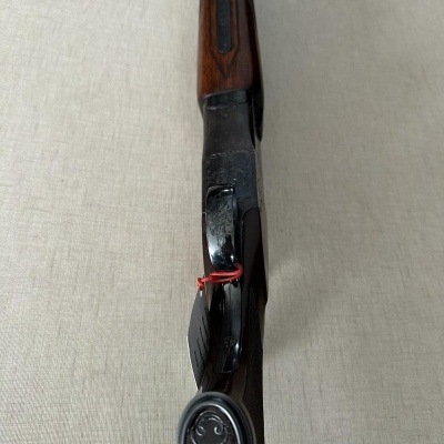 Carabina de madeira com detalhes em metal preto e laço vermelho