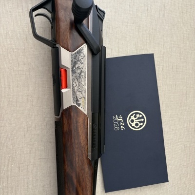 Espingarda de caça com detalhes em madeira e metal ao lado de caixa azul com símbolo e texto Beretta.
