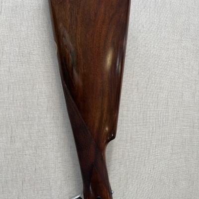 Coronha de espingarda em madeira escura polida com detalhes metálicos