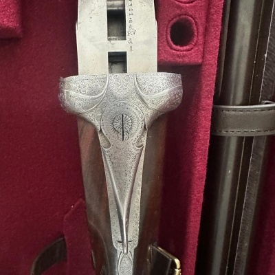 Espingarda de caça com coronha de madeira e gravações em metal prateado numa caixa vermelha de veludo