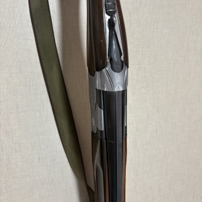 Espingarda com madeira castanha e metal prateado contra fundo claro