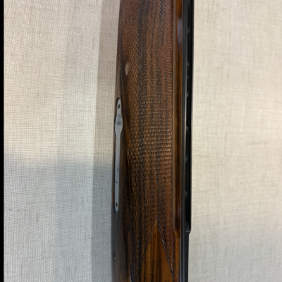 Coronha de espingarda em madeira escura polida com detalhes metálicos prateados