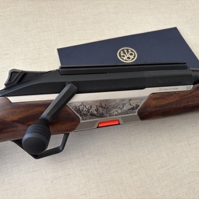 Carabina de caça Beretta com detalhes em madeira castanha e metal prateado gravado com cena da natureza