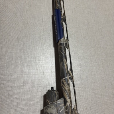 Espingarda com padrão camuflado e peça azul com texto BRATTA