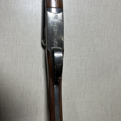 Espingarda com madeira castanha e metal prateado com texto CHOKE