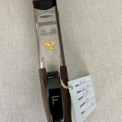 Punho de arma em madeira e metal com gravações e etiqueta branca com texto