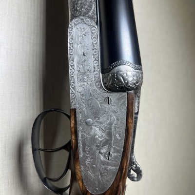 Espingarda de canos duplos com madeira escura e acabamentos metálicos gravados