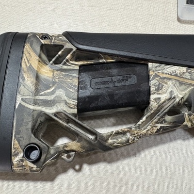 Coronha de arma com padrão camuflado e almofada preta com texto