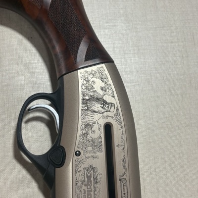 Arma de fogo com empunhadura em madeira castanha, corpo metálico beige com gravações detalhadas e gatilho metálico