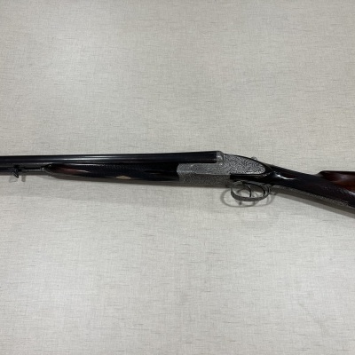 Espingarda de caça de cano duplo com cabo em madeira escura sobre tecido bege