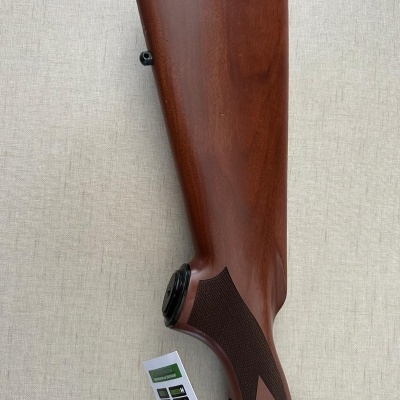 Coronha de madeira castanha com detalhes pretos sobre fundo bege.