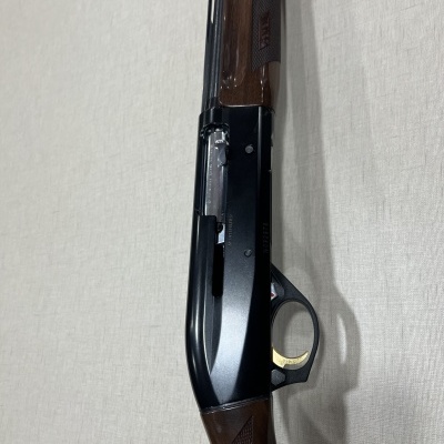 Espingarda de caça em madeira castanha e metal preto com fundo claro