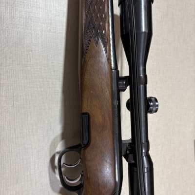 Rifle de madeira castanha com visor óptico preto montado no cano