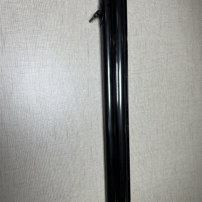 Parte do cano de uma espingarda de canos paralelos em metal preto sobre superfície cinzenta