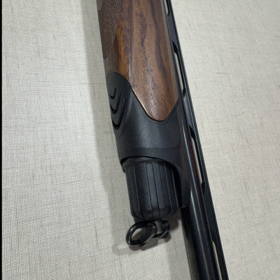 Coronha de espingarda em madeira castanha com entalhes e cano preto fosco.