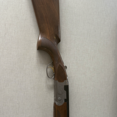 Espingarda de madeira e metal encostada em parede clara