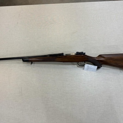 Rifle de coronha em madeira escura com cano longo sobre superfície clara