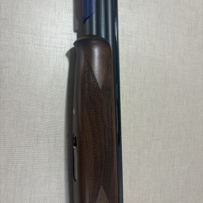 Espingarda com coronha de madeira escura e canos metálicos azuis