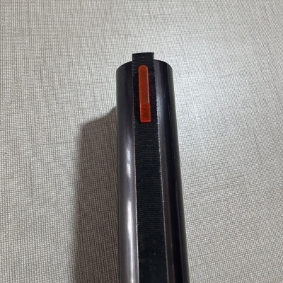 Arma de fogo preta com mira vermelha sobre tecido claro