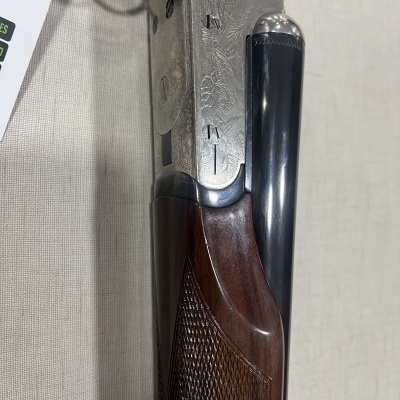 Espingarda com madeira escura, metal gravado e cano preto