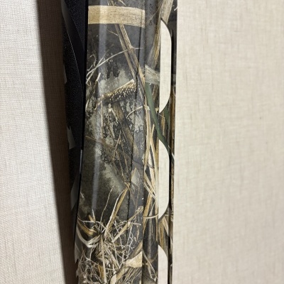 Arma camuflada com padrão de vegetação seca e texto BERETTA USA CORP. ACKK MD