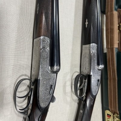 Duas espingardas com coronhas de madeira e detalhes metálicos prateados