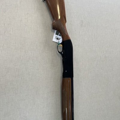 Espingarda com madeira castanha e metal preto sobre superfície bege