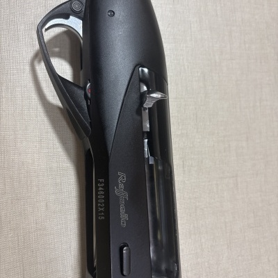 Espingarda Raffaello com coronha de madeira e corpo preto com gravações visíveis.