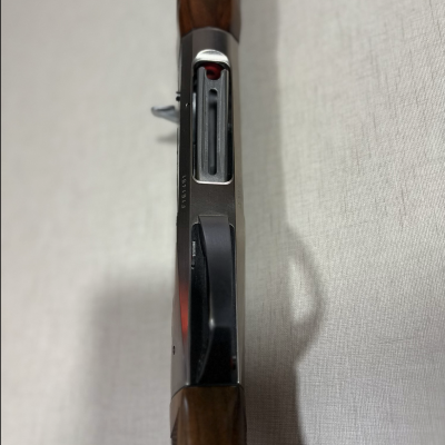 Espingarda de cano duplo com empunhadura de madeira e corpo metálico preto e prata