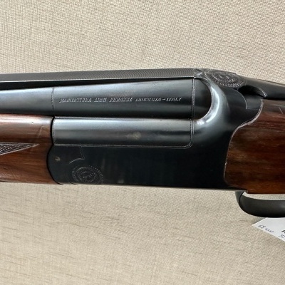 Espingarda de canos duplos com detalhes em madeira e metal, texto gravado no cano