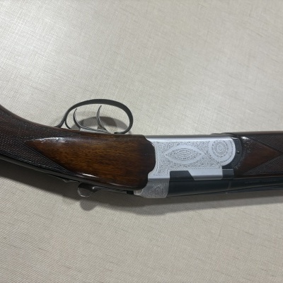 Espingarda de caça em madeira escura com detalhes metálicos cinzentos gravados