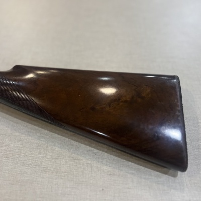 Puxador de arma em madeira polida castanha sobre superfície clara