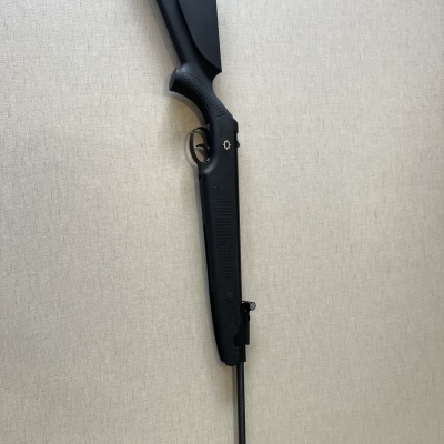 Espingarda preta com coronha e cano longo sobre fundo cinza