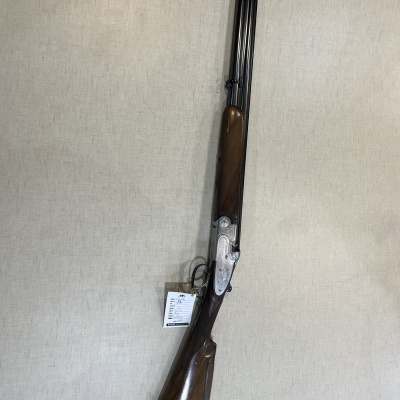 Espingarda de canos duplos com madeira castanha e metal prateado pendurada na parede