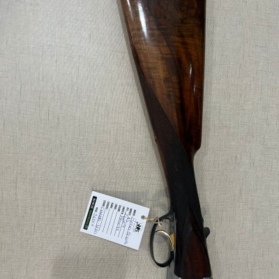 Espingarda com coronha de madeira polida castanha e partes metálicas prateadas