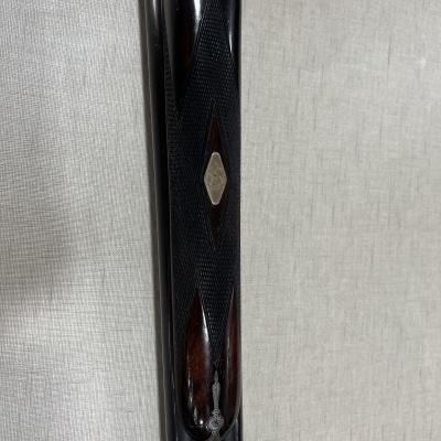 Parte de espingarda com cabo em madeira escura e detalhes texturizados