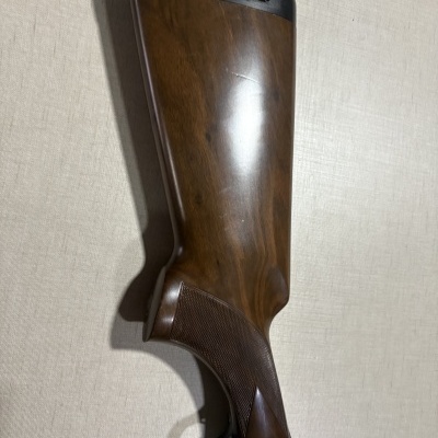 Coronha de espingarda de madeira castanha com punho texturizado e amortecedor preto.