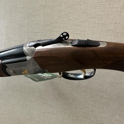 Espingarda de canos duplos com acabamento em madeira castanha e metal gravado