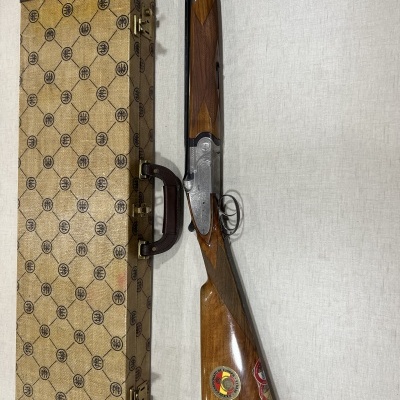 Arma de caça de cano duplo com madeira e mala de transporte bege com padrão