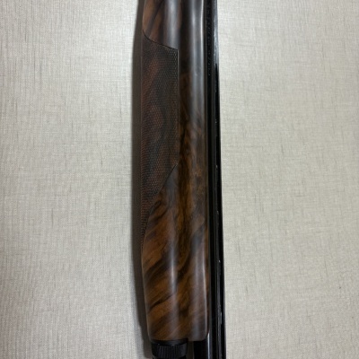 Espingarda com acabamento em madeira castanho e metal preto sobre fundo claro