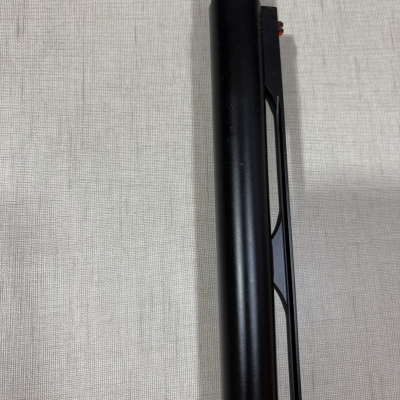 Cano preto cilíndrico fosco com parte superior texturizada e estrutura preta sobre fundo tecido cinza