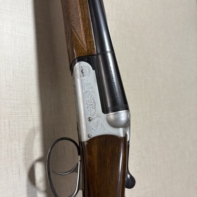 Espingarda de canos duplos com madeira e metal escuro, com gravações e texto PIETRO BERETTA GARDONE V.T. MADE IN ITALY.