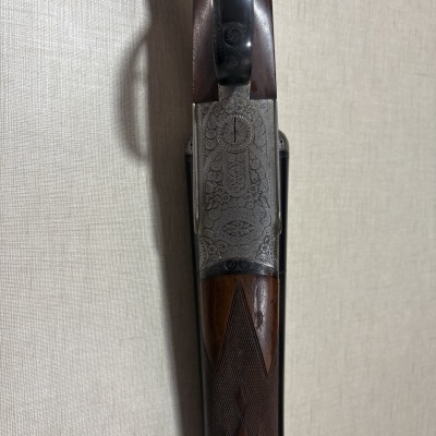 Espingarda com cabo de madeira castanha e metal gravado com padrões florais.