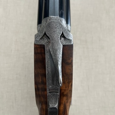 Espingarda de canos pretos e madeira trabalhada com detalhes gravados